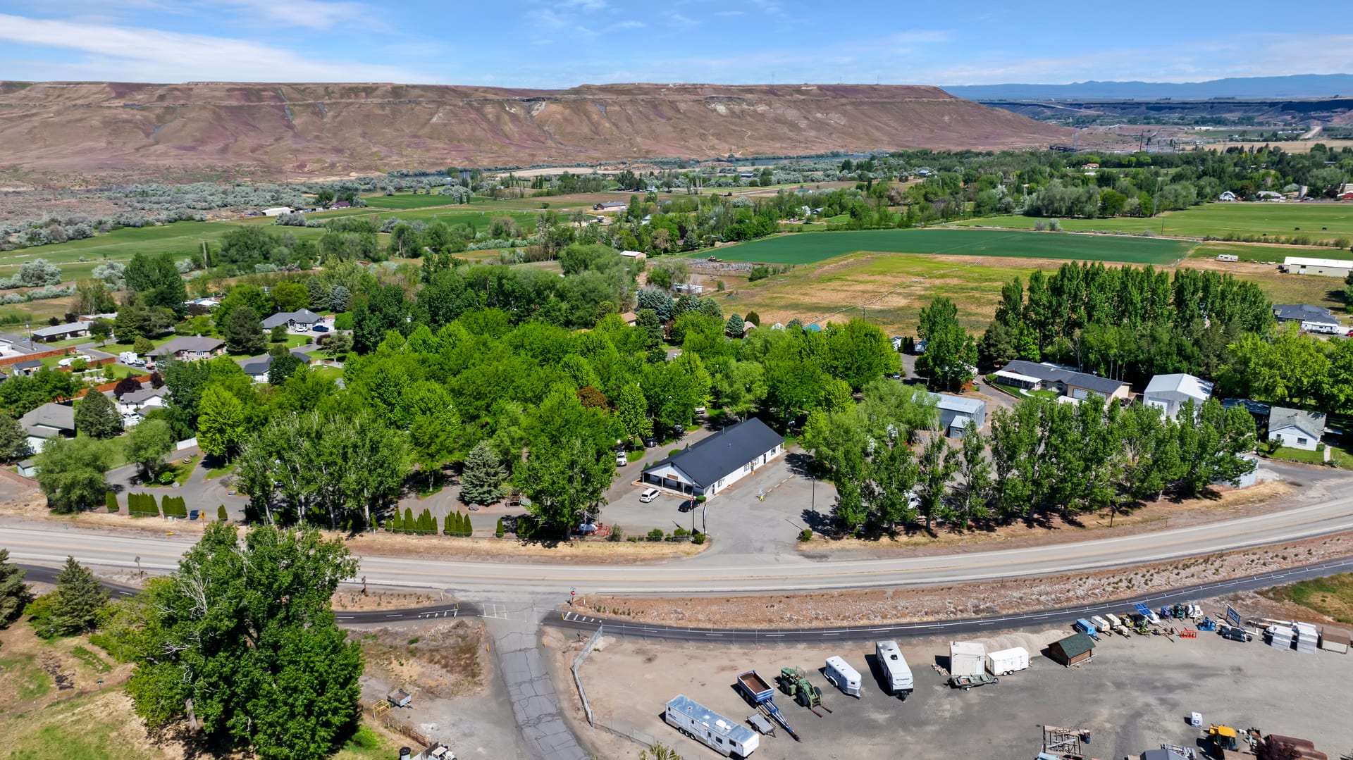 Aerial view of Hagerman RV Village's tree-shaded sites along Highway 30, with the Snake River canyon rim beyond